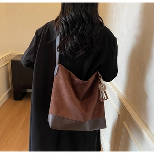 Detail of vintage brown suede hobo bag with adjustable strap and plush pendant