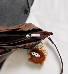 Dettaglio della cerniera su borsa a secchiello marrone con ciondolo in peluche morbido