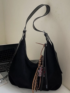 Minimalist black faux suede hobo bag with wide shoulder strap and woven tassel charm