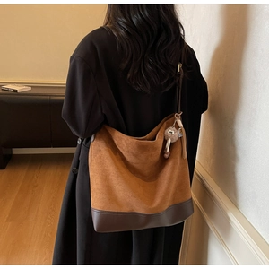 Detail of vintage brown suede tote bag with plush charm on model in neutral room