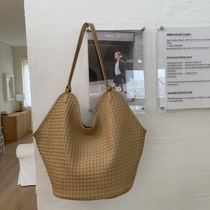 Detailed texture of khaki woven bucket bag hanging on a minimalist white wall