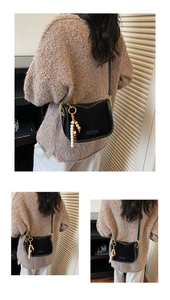 Detail of black suede shoulder bag with retro wooden beads and adjustable leather strap