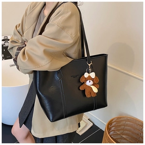 Detail of black PU leather tote bag featuring fashion lettering and a cute bear charm