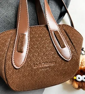 Dettaglio delle cuciture in pelle marrone e della trama del tessuto a maglia della borsa