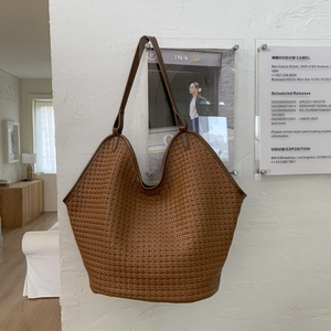 Close-up detail of caramel woven texture on large capacity bucket tote shoulder bag