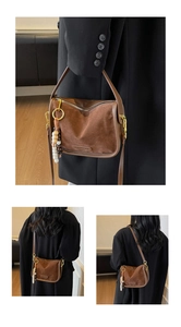 Detail of suede crossbody bag with vintage wooden bead tassels and golden hardware