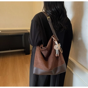 Detail of brown suede hobo bag with leather patchwork and a cute plush doll charm