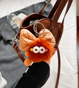 Dettaglio del ciondolo mostro di peluche marrone con fiocco su borsa in pelle