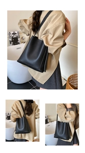 Detail view of large capacity black pebbled leather bucket bag with long shoulder strap