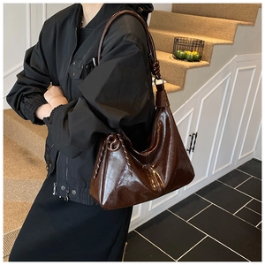 Détail du sac sous le bras en cuir marron foncé avec bandoulière à nœud et surpiqûres