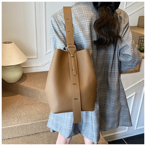 Close-up of caramel brown pebble leather bucket bag with adjustable wide shoulder strap