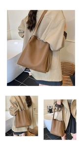 Close-up of the pebbled brown leather texture and wide shoulder strap on the bucket bag