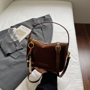 Detail showing deep coffee suede stitching and gold-tone hardware of the fashion bag