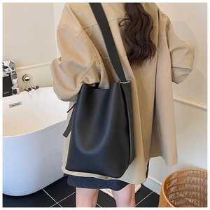 Detail view of large black litchi grain leather bucket bag with wide shoulder strap