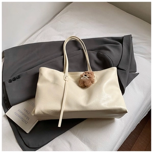 Detailed macro view of cream tote bag leather texture with brown plush bear charm