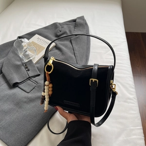 Detail of minimalist black suede and leather handbag with gold hardware on white background