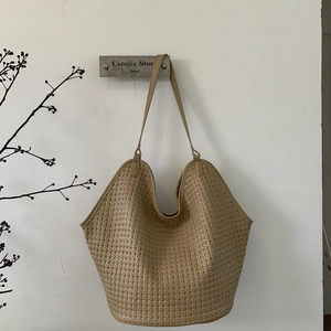 Detailed close-up of apricot woven bucket tote bag with lightweight texture and thin strap