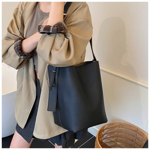 Detail view of black lychee grain leather bucket bag with long side strap decoration