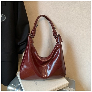Vue détaillée de la bandoulière nouée et du sac hobo en cuir bordeaux brillant