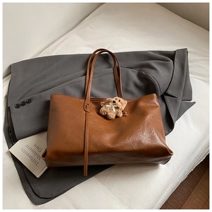 Detail of vintage brown textured faux leather tote bag with a cute plush bear pendant
