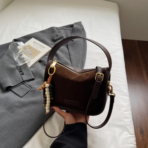 Detailed close-up of suede and leather textures on brown bag with decorative beads