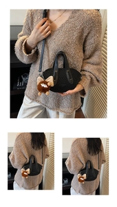 Dettaglio di borsa nera a contrasto con ciondolo in peluche marrone e tracolla chic