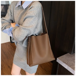 Detail of dark brown leather bucket bag with adjustable strap and pebble grain texture
