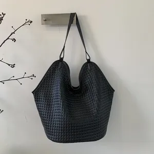 Detail of hand-woven black leather bucket bag showing large capacity and matte texture