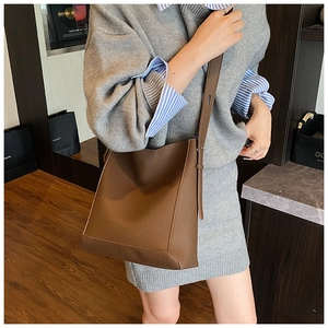 Detailed view of the dark brown lychee grain leather bucket bag with slim shoulder strap