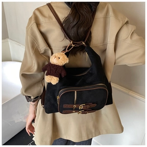Dettaglio borsa a spalla vintage nera opaca con finiture in pelle marrone e charm orso
