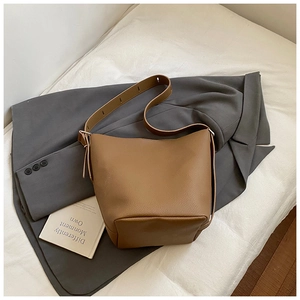 Brown leather bucket bag with pebble texture styled on a grey blazer for a chic look