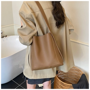 Brown lychee leather bucket bag showing large capacity and drape on a model's shoulder