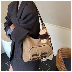 Dettaglio della borsa hobo in pelle scamosciata kaki con tasca a zip e ciondolo a orsetto