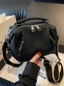 Black pebbled leather Boston bag with multiple zippers and a wide fabric strap