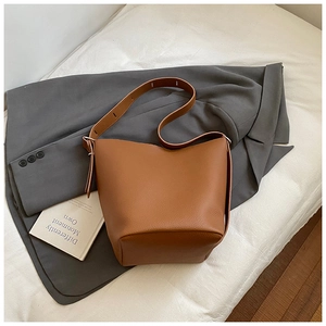 Close-up of brown litchi pattern leather bucket bag with an adjustable wide shoulder strap