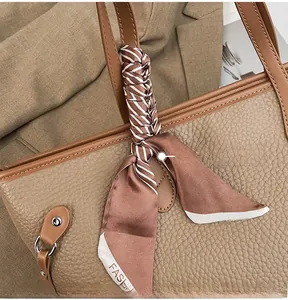 Detail of tan pebble leather tote with striped silk scarf and elegant stitching