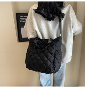 Modello con borsa tote trapuntata nera a rombi grandi in un ambiente urbano moderno