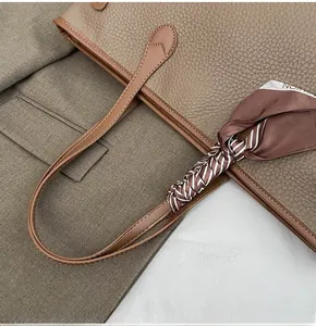 Detailed view of brown lychee grain leather tote with striped silk scarf on handle