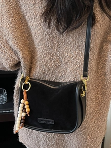 Fashionable black leopard-style patchwork handbag with bohemian beads on beige sweater