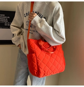 Borsa tote trapuntata arancione con trama a rombi indossata a tracolla da una modella