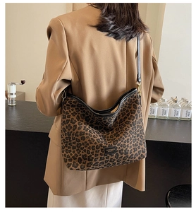 Detail of leopard print hobo bag worn by model in a brown blazer at a bar setting