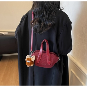 Dettaglio mini borsa a secchiello in tweed rosso con manico in pelle e ciondolo mostro