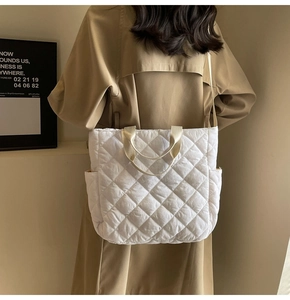Dettaglio della borsa tote trapuntata bianca indossata con cappotto beige in stile minimal