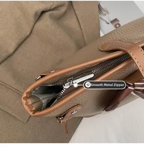 Close-up of smooth silver metal zipper on a brown pebbled leather tote bag for women