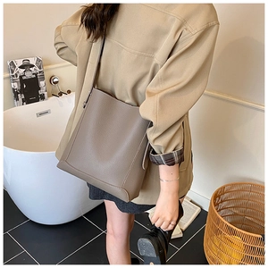 Macro detail of taupe lychee leather bucket bag with seamless shoulder strap