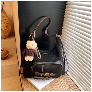Dettaglio dello zaino vintage in pelle scamosciata nera con finiture e ciondolo a orso