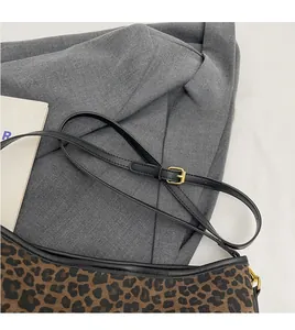 Detail of adjustable black strap with gold buckle on leopard print bucket shoulder bag