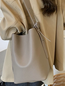 Minimalist khaki leather shoulder bag with pebbled texture and adjustable strap worn by model