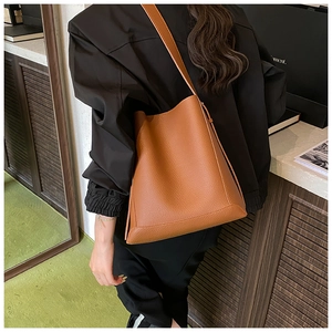 Detail of brown litchi textured leather bucket bag with shoulder strap and drawstring