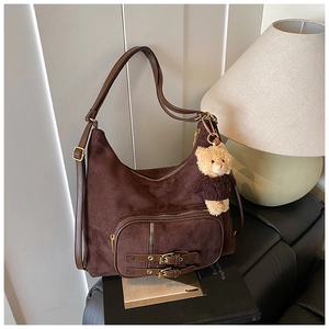 Dettaglio della borsa hobo in pelle scamosciata marrone con tasca e ciondolo a orsetto